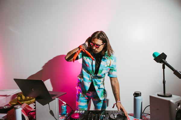 One of our DJs in Los Angeles for parties wearing matching Hawaiian themed shirt and shorts while posing with DJ equipment for picture | Altus Entertainment